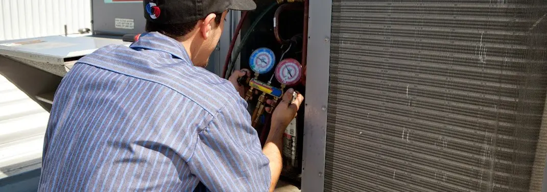 HVAC technician servicing a condenser unit in Meadowbrook